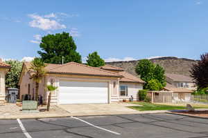 Mediterranean / spanish house featuring stucco siding, a tiled roof, a garage, central air condition unit, and concrete driveway, community pool