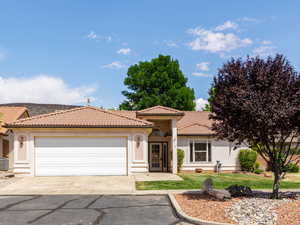 Mediterranean / spanish house with stucco siding, concrete driveway, a tile roof, an attached garage, and central AC