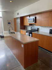 Kitchen featuring stainless steel appliances, tile backsplash, concrete countertops, and modern cabinets