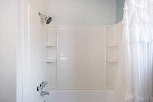 Bathroom view of shower / bathtub combination with curtain
