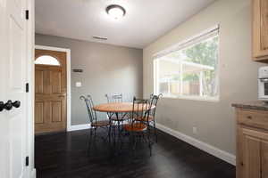 Dining area with dark wood-style flooring and baseboards