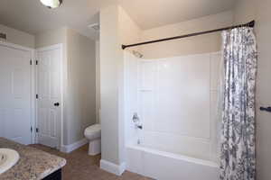 Bathroom featuring shower / tub combo with curtain, vanity, toilet, baseboards, and tile patterned floors