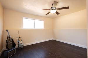 Spare room with dark wood-style flooring, baseboards, ceiling fan, and a textured ceiling