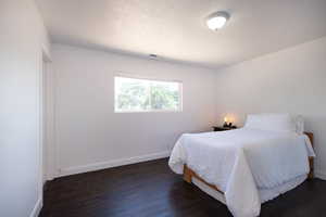 Bedroom featuring baseboards, dark wood finished floors, and a textured ceiling