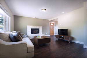 Living area featuring dark wood-style flooring, baseboards, and a fireplace