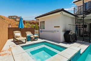 View of swimming pool with an in-ground hot tub, a patio area, and a grill