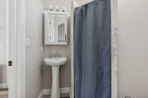 Bathroom with a shower with curtain, a sink, and baseboards