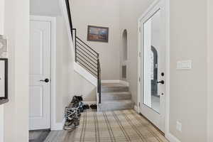 Foyer featuring arched walkways, stairs, and baseboards