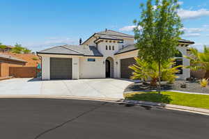 View of front facade featuring a garage, concrete driveway, stucco siding, and a tile roof