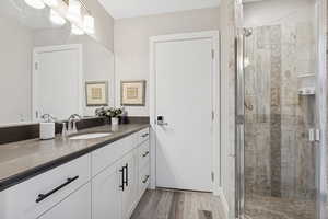 Full bath featuring vanity, a stall shower, and wood finished floors