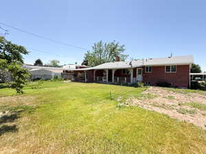 Rear view of property featuring a lawn, brick siding, and a chimney