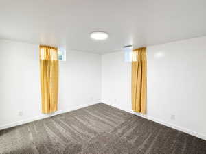 Spare room featuring baseboards and dark carpet