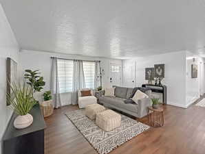 Living area with baseboards, wood finished floors, and a textured ceiling