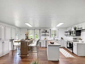 Kitchen with stainless steel electric stove, a center island, open shelves, plenty of natural light, and a textured ceiling