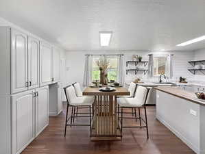 Dining room with plenty of natural light, dark wood-style flooring, a textured ceiling, and baseboards