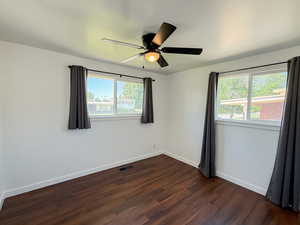 Unfurnished room with dark wood-type flooring, baseboards, and ceiling fan