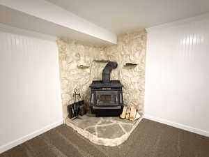 Detailed view of a wood stove, carpet floors, and baseboards