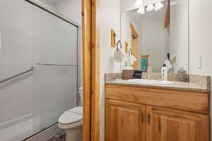 Bathroom featuring toilet, vanity, and a shower stall