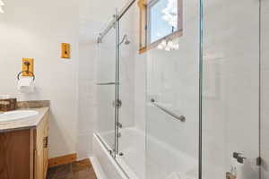 Bathroom with baseboards, vanity, and bath / shower combo with glass door