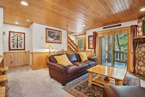 Living room featuring a wainscoted wall, wooden ceiling, recessed lighting, wood walls, and light colored carpet