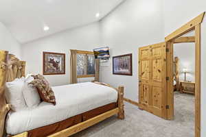 Carpeted bedroom with high vaulted ceiling and baseboards
