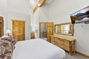 Bedroom featuring a high ceiling, carpet, and ensuite bathroom