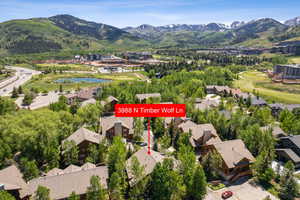 Aerial view of residential area featuring a pond and mountain view and a golf course