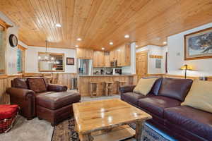 Living area featuring wooden ceiling, a wainscoted wall, light carpet, a chandelier, and recessed lighting