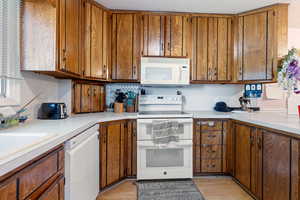 Kitchen featuring white appliances, brown cabinets, and light countertops