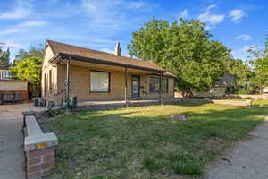 View of front of home featuring central air condition unit, a front yard, a chimney, and brick siding