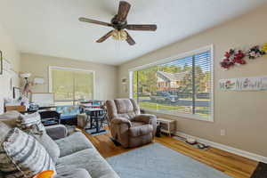 Living area with a ceiling fan, wood finished floors, and baseboards