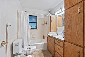 Bathroom with vanity, toilet, and shower / bathtub combination with curtain