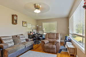 Living area with wood finished floors, plenty of natural light, and a ceiling fan