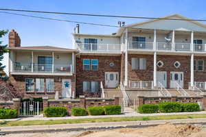 Townhome / multi-family property with a balcony, a chimney, a fenced front yard, and brick siding