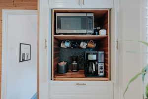 Bar featuring stainless steel microwave and decorative backsplash