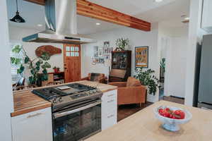 Kitchen featuring island range hood, butcher block countertops, gas range, white cabinets, and dark wood finished floors