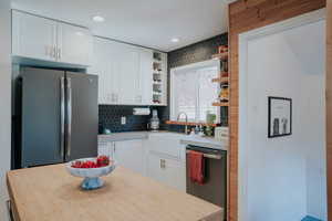 Kitchen with stainless steel appliances, open shelves, a sink, white cabinets, and recessed lighting