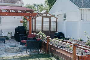 View of patio / terrace with an exterior structure, a garden, an outdoor structure, an outdoor fire pit, and area for grilling