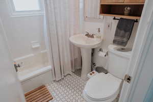 Full bathroom featuring toilet, shower / tub combo with curtain, and a sink