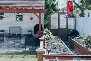View of patio featuring an exterior structure, an outbuilding, a garden, a fire pit, and a grill
