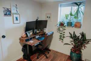 Home office with dark wood-type flooring and baseboards