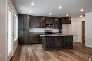 Kitchen featuring stainless steel appliances, a sink, dark brown cabinets, dark wood-style flooring, and recessed lighting