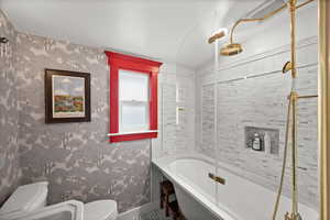 Full bath with toilet, baseboards, and a combined bath / shower with rainfall shower