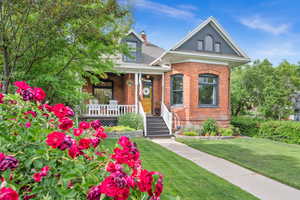 View of front of property with a porch, brick siding, and a front yard