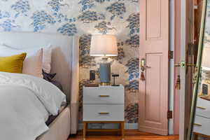 Bedroom with wood finished floors and wallpapered walls