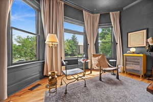 Sitting room featuring healthy amount of natural light, wood finished floors, and ornamental molding