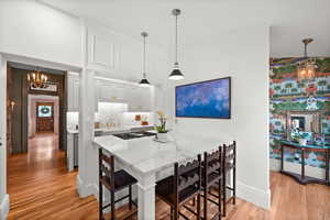 Kitchen featuring a chandelier, gas cooktop, light wood-type flooring, a breakfast bar area, and light stone counters