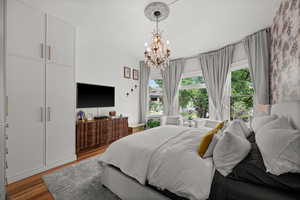 Bedroom with multiple windows, a chandelier, and wood finished floors