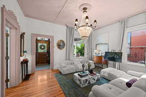 Living area featuring a chandelier, light wood-style floors, and ornamental molding