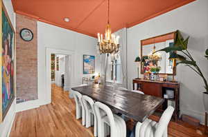 Dining area with a chandelier, crown molding, wood finished floors, and baseboards